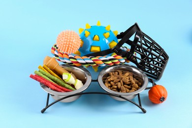 Photo of Dry pet food, toys and other goods on light blue background. Shop items