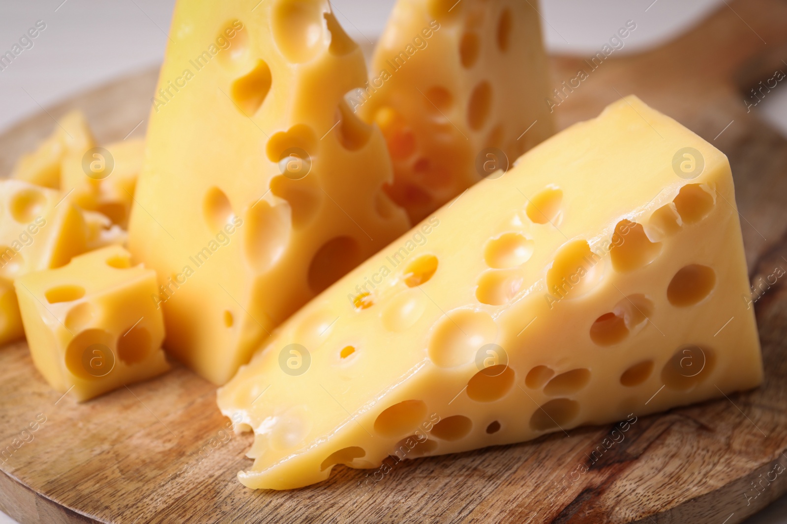 Photo of Pieces of delicious cheese on wooden board, closeup