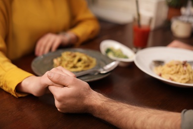 Lovely couple holding hands at table in restaurant, closeup view