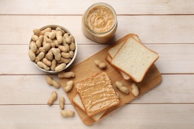 Photo of Delicious toasts with peanut butter and nuts on light wooden table, flat lay