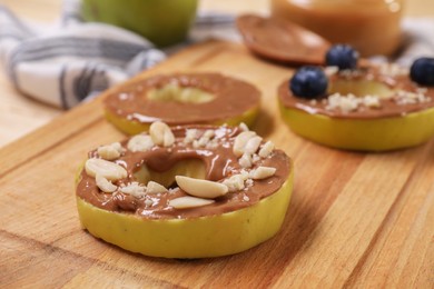 Photo of Slices of fresh apple with nut butter and peanuts on wooden board, closeup