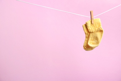 Photo of Small socks hanging on washing line against color background, space for text. Baby accessories