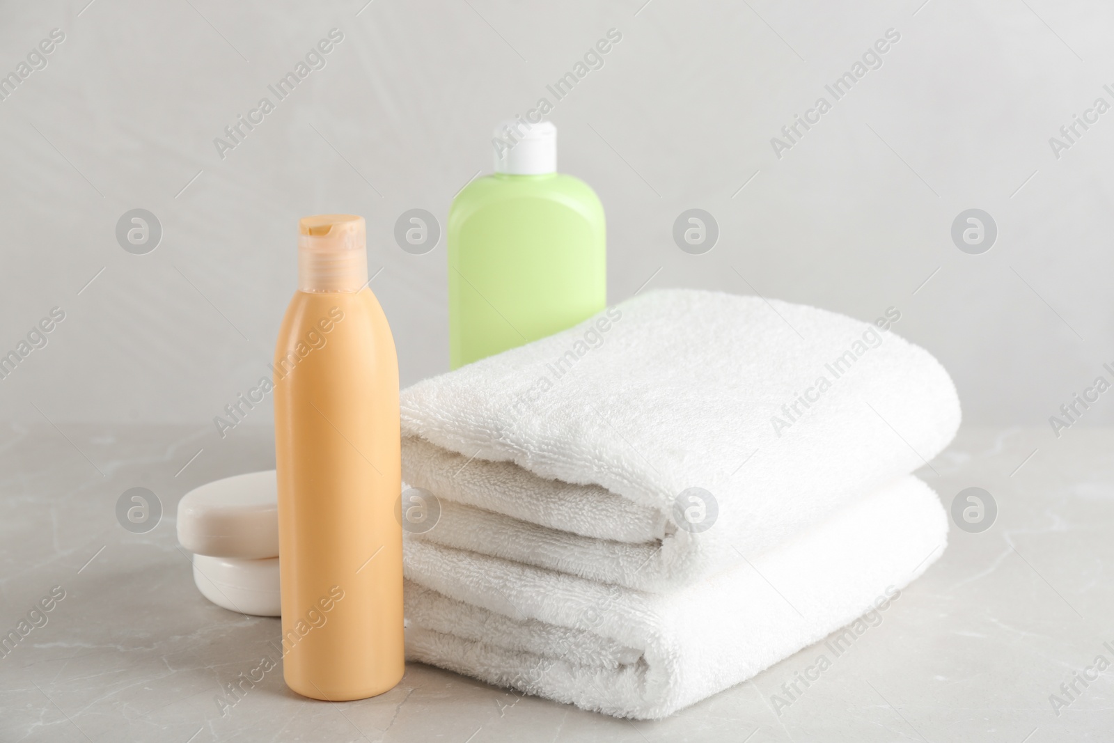 Photo of Fresh towels and toiletries on light grey marble table