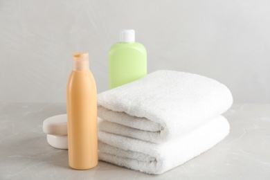 Photo of Fresh towels and toiletries on light grey marble table