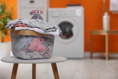 Photo of Laundry basket with baby clothes and toy on table in bathroom. Space for text