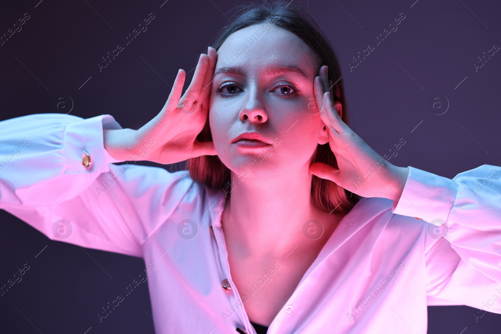 Photo of Fashionable portrait of beautiful young woman on purple background in neon lights