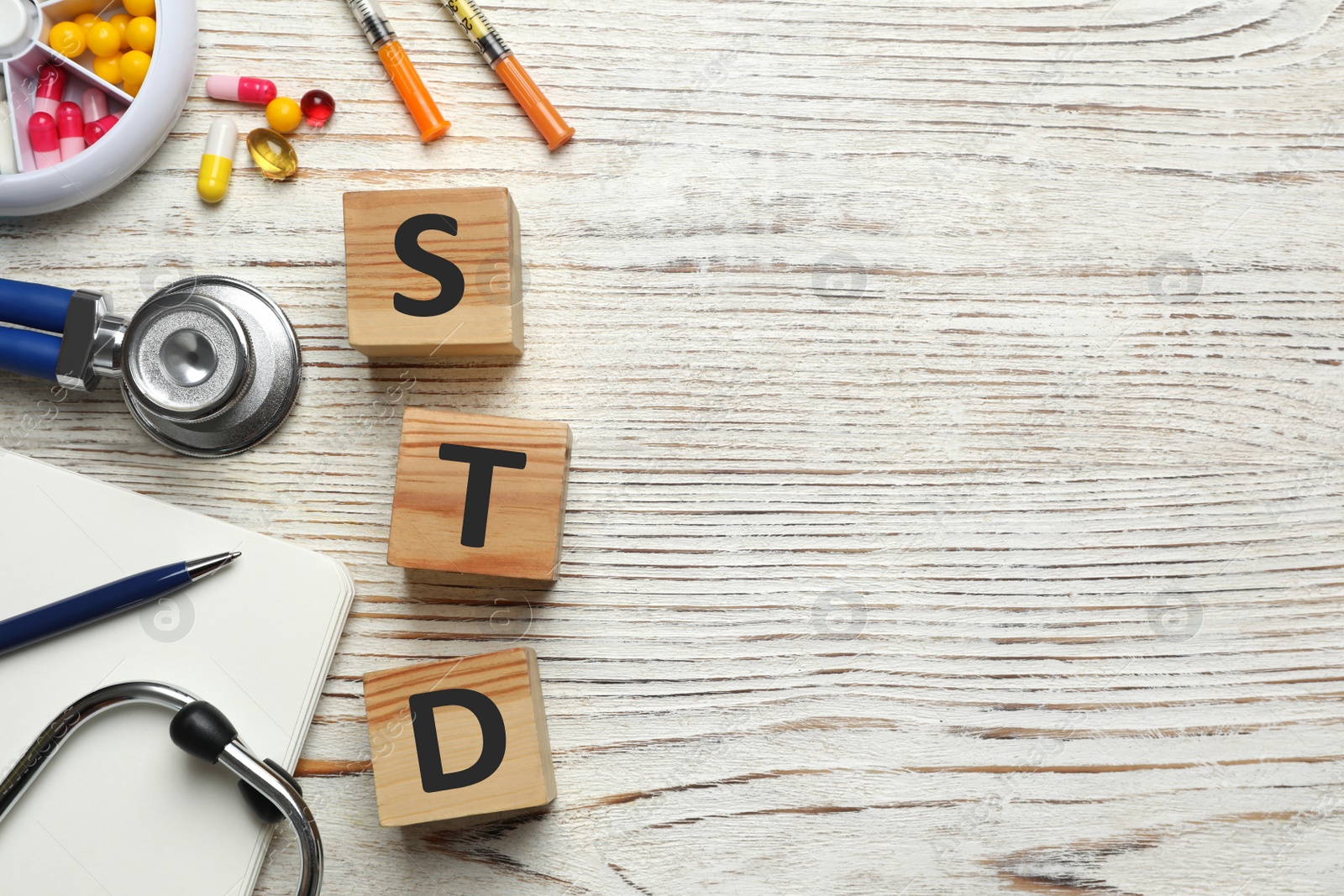 Photo of Flat lay composition with abbreviation STD and stethoscope on white wooden table. Space for text