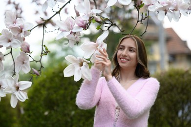 Beautiful young woman near blossoming magnolia tree on spring day