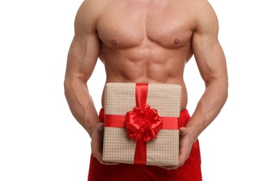 Photo of Attractive young man with muscular body in Santa hat holding Christmas gift box on white background, closeup