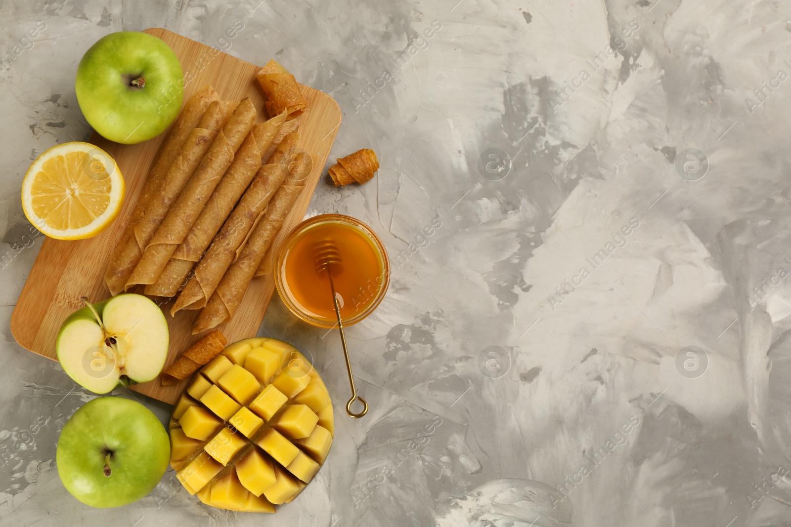 Photo of Flat lay composition with delicious fruit leather rolls on table. Space for text