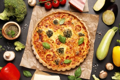 Delicious homemade vegetable quiche and products on black table, flat lay