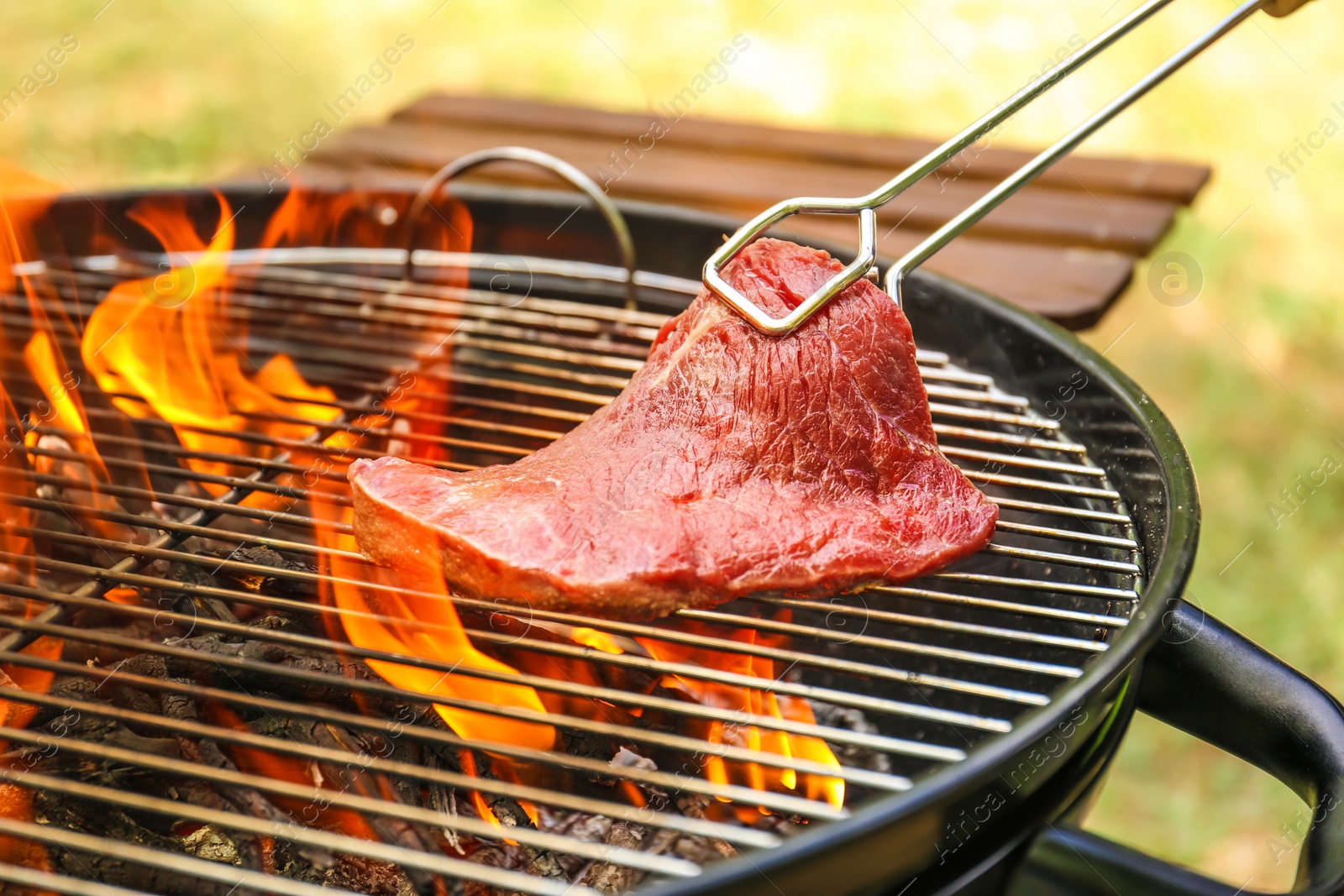 Photo of Tasty meat on barbecue grill with fire flames outdoors, closeup