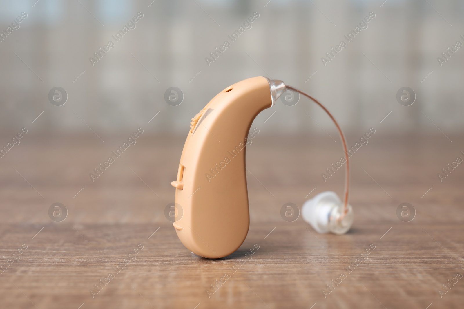 Photo of Hearing aid on wooden table, closeup. Medical device