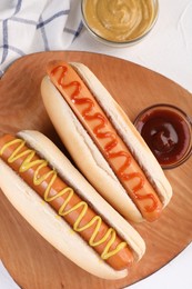 Photo of Tasty hot dogs with ketchup and mustard on white table, flat lay