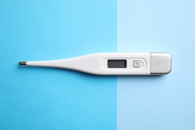 Modern digital thermometer on color background, top view