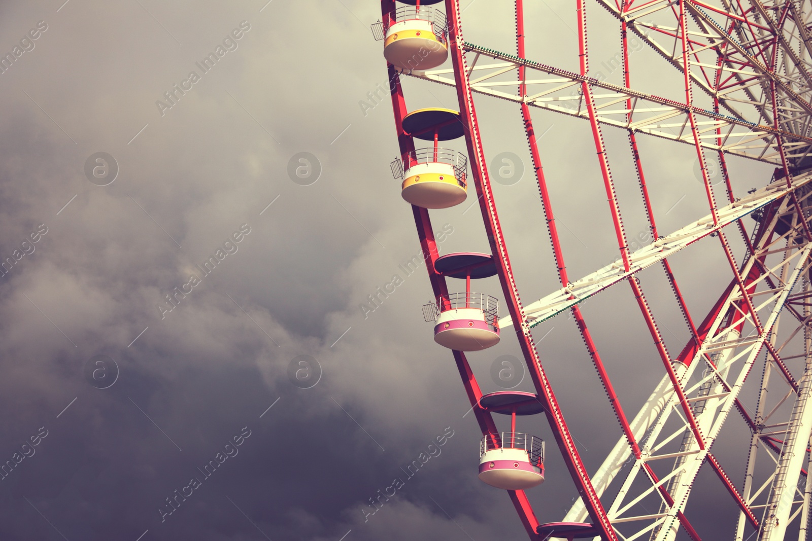 Image of Beautiful large Ferris wheel against heavy rainy clouds outdoors, space for text