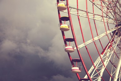 Beautiful large Ferris wheel against heavy rainy clouds outdoors, space for text