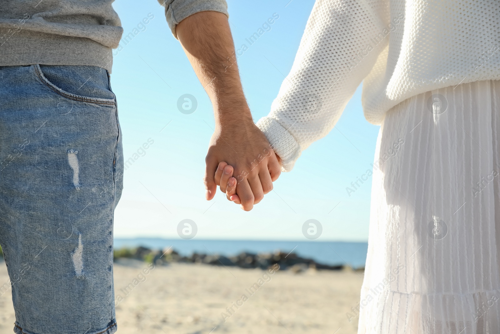 Photo of Young couple holding hands on beach, closeup. Honeymoon trip