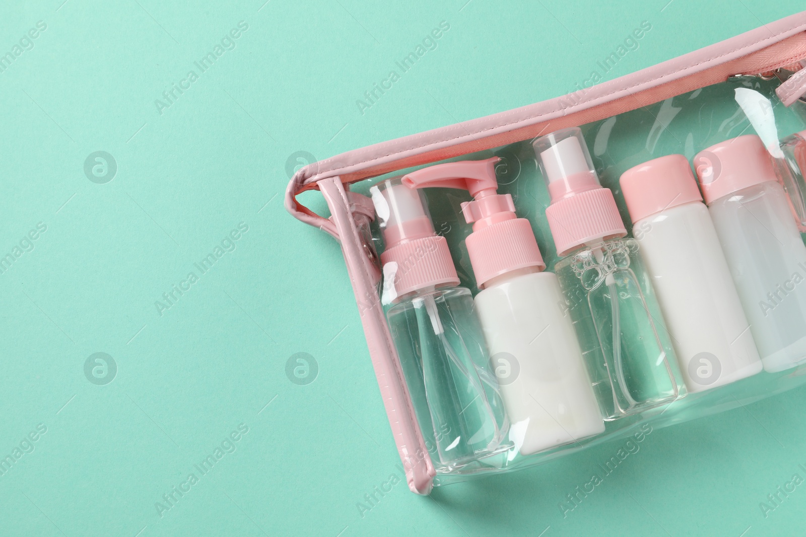 Photo of Cosmetic travel kit in plastic bag on turquoise background, top view. Space for text