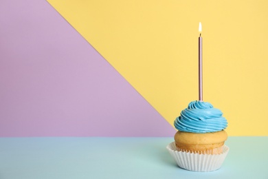 Photo of Birthday cupcake with candle on color background, space for text