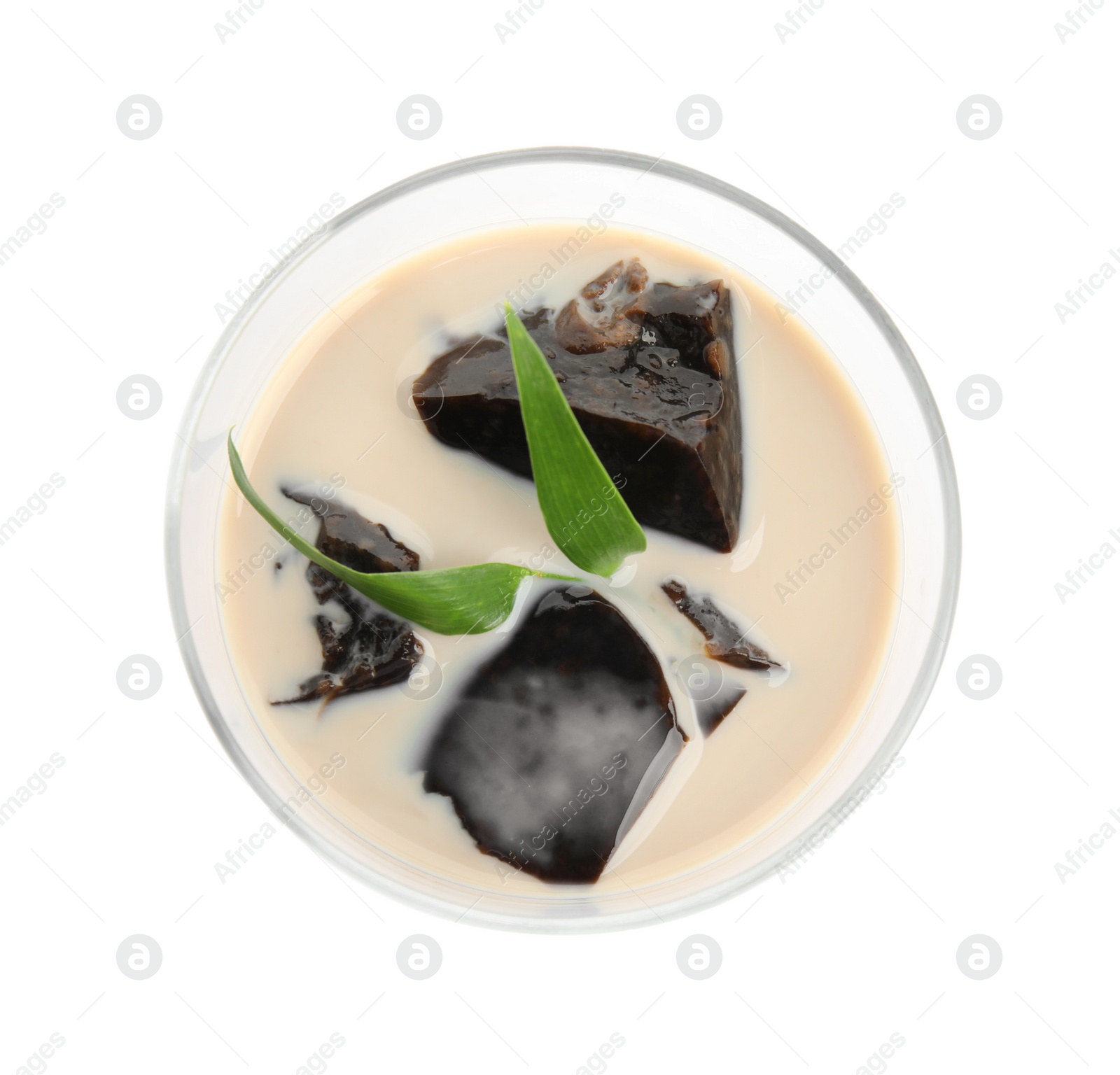 Photo of Glass of milk with grass jelly and green leaves isolated on white, top view