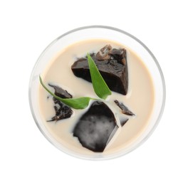 Photo of Glass of milk with grass jelly and green leaves isolated on white, top view