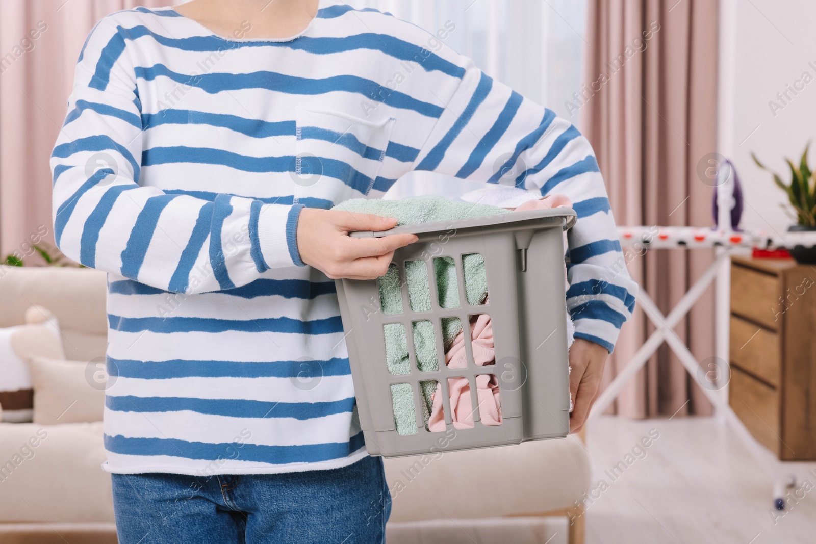 Photo of Woman with basket full of laundry at home, closeup