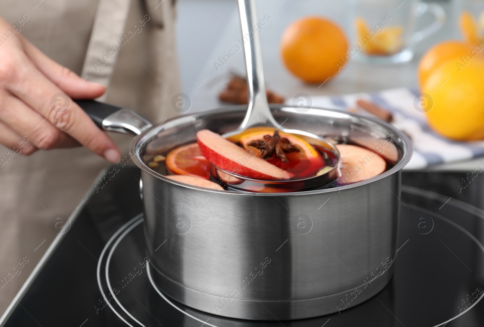 Photo of Woman cooking delicious mulled wine at stove, closeup