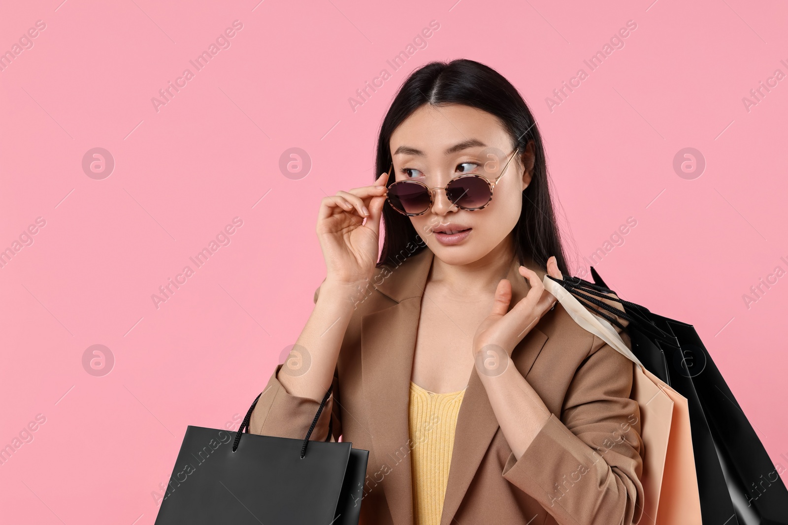 Photo of Beautiful woman with shopping bags on pink background. Space for text