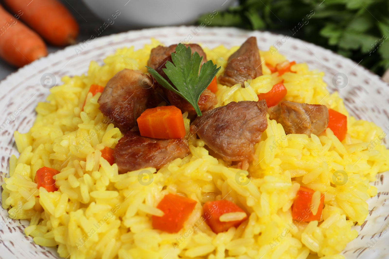 Photo of Delicious pilaf with meat and carrot on white plate, closeup