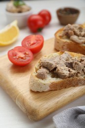 Photo of Tasty sandwiches with cod liver on white wooden table