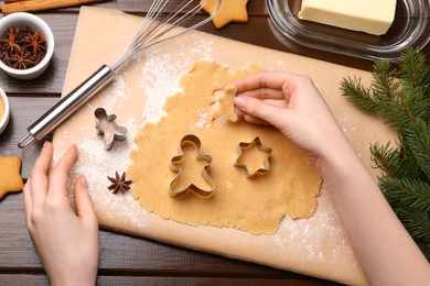 Photo of Woman making Christmas cookies with cutters at wooden table, top view