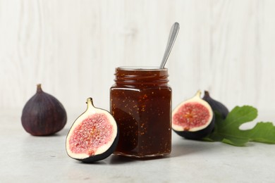 Photo of Glass jar with tasty sweet jam and fresh figs on white table