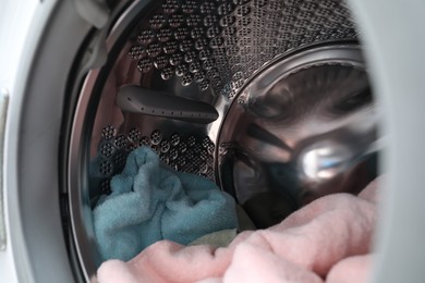 Photo of Modern washing machine drum with laundry, closeup