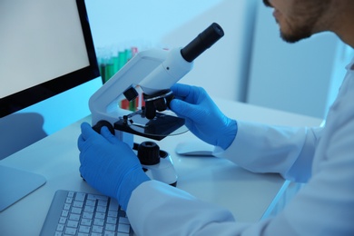Medical student working with microscope in modern scientific laboratory, closeup
