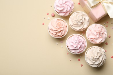 Delicious birthday cupcakes, gift box and sprinkles on beige background, flat lay. Space for text