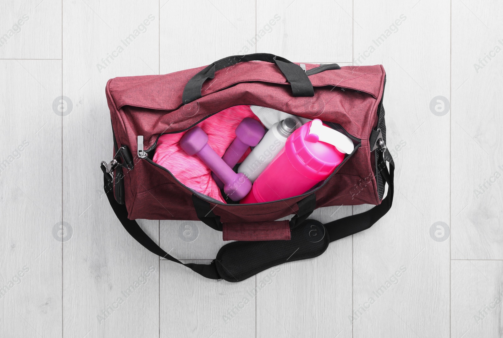 Photo of Sports bag with gym stuff on white floor, top view