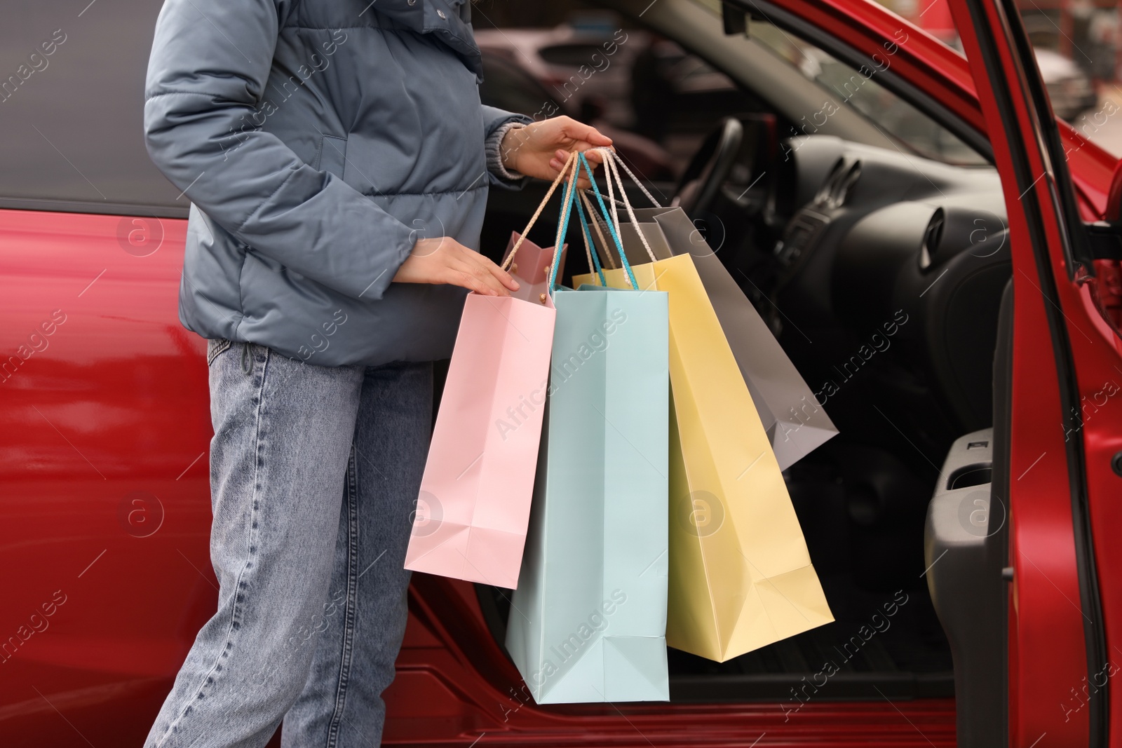 Photo of Woman with shopping bags near her car outdoors, closeup