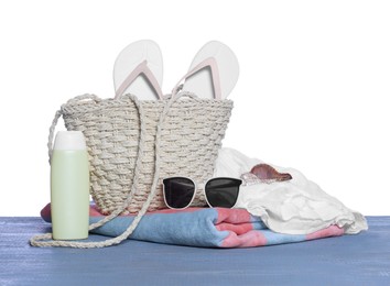 Photo of Stylish bag, sunscreen and other beach accessories on grey wooden table against white background