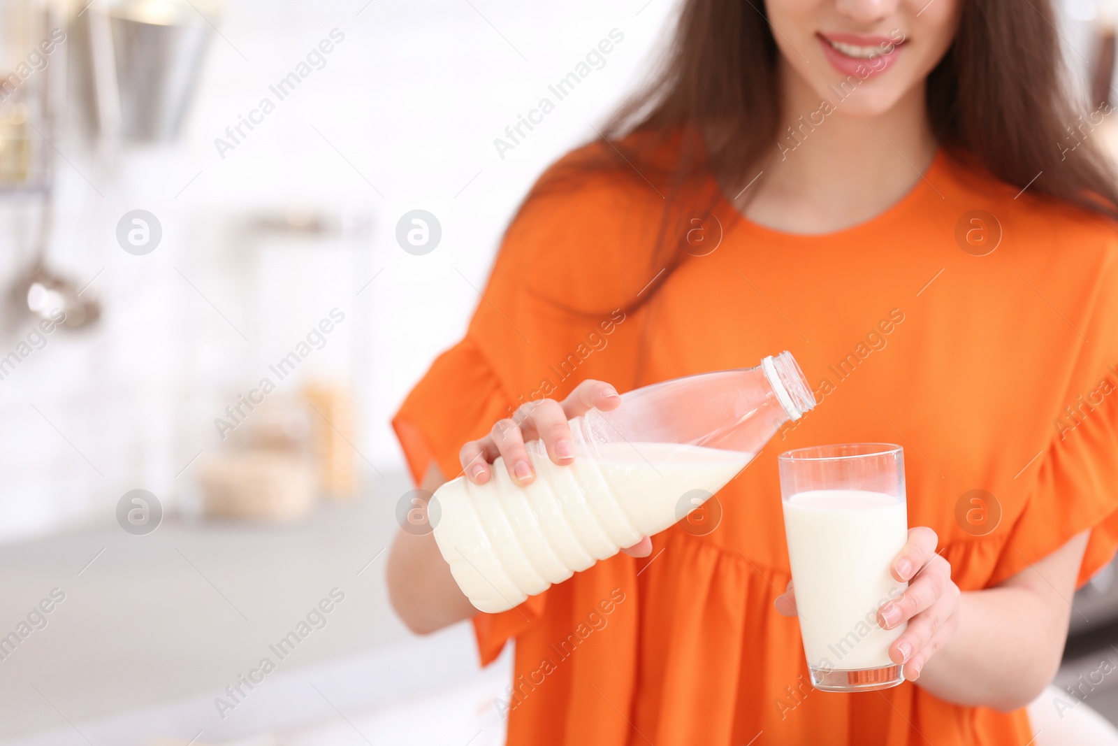 Photo of Beautiful young woman drinking milk in kitchen