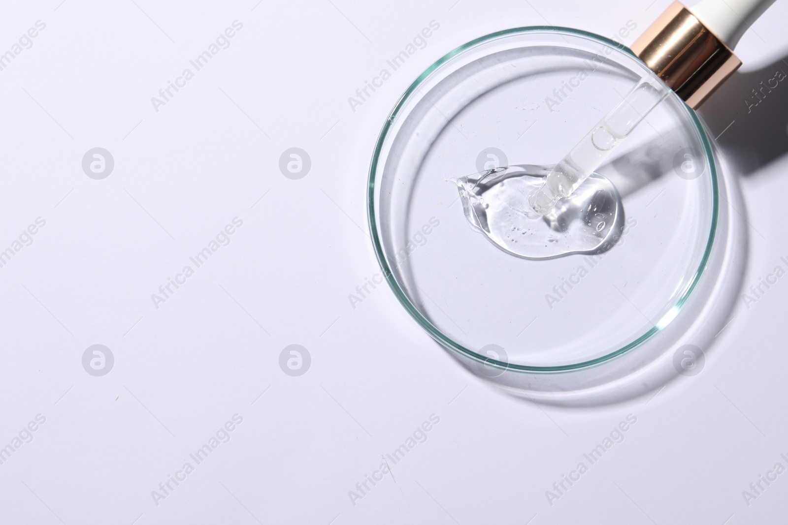 Photo of Petri dish with sample of cosmetic serum and pipette on white background, top view. Space for text