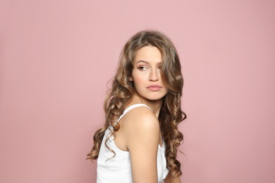 Portrait of beautiful young woman with shiny wavy hair on color background