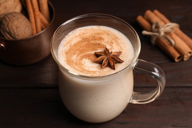 Photo of Delicious eggnog with spices on wooden table