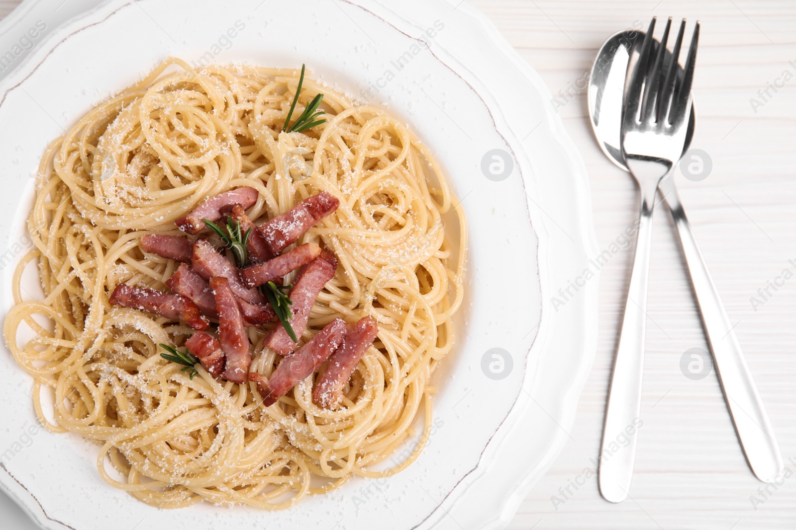 Photo of Delicious Carbonara pasta served on white wooden table, flat lay