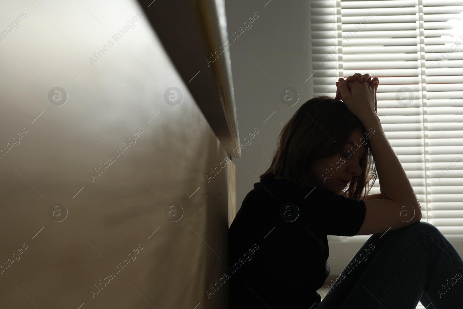 Photo of Sad young woman sitting indoors, space for text