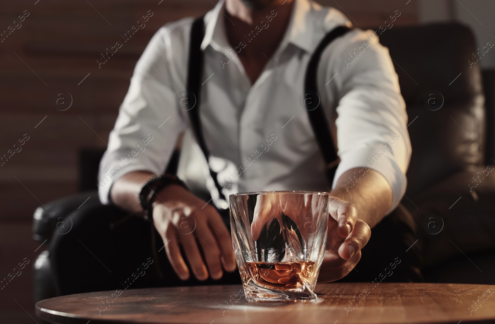 Photo of Man with glass of whiskey sitting at table, closeup