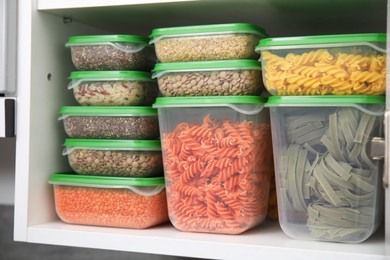 Photo of Plastic containers filled with food products in kitchen cabinet, closeup