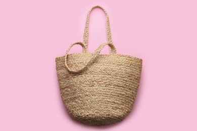 Photo of Elegant woman's straw bag on pink background, top view