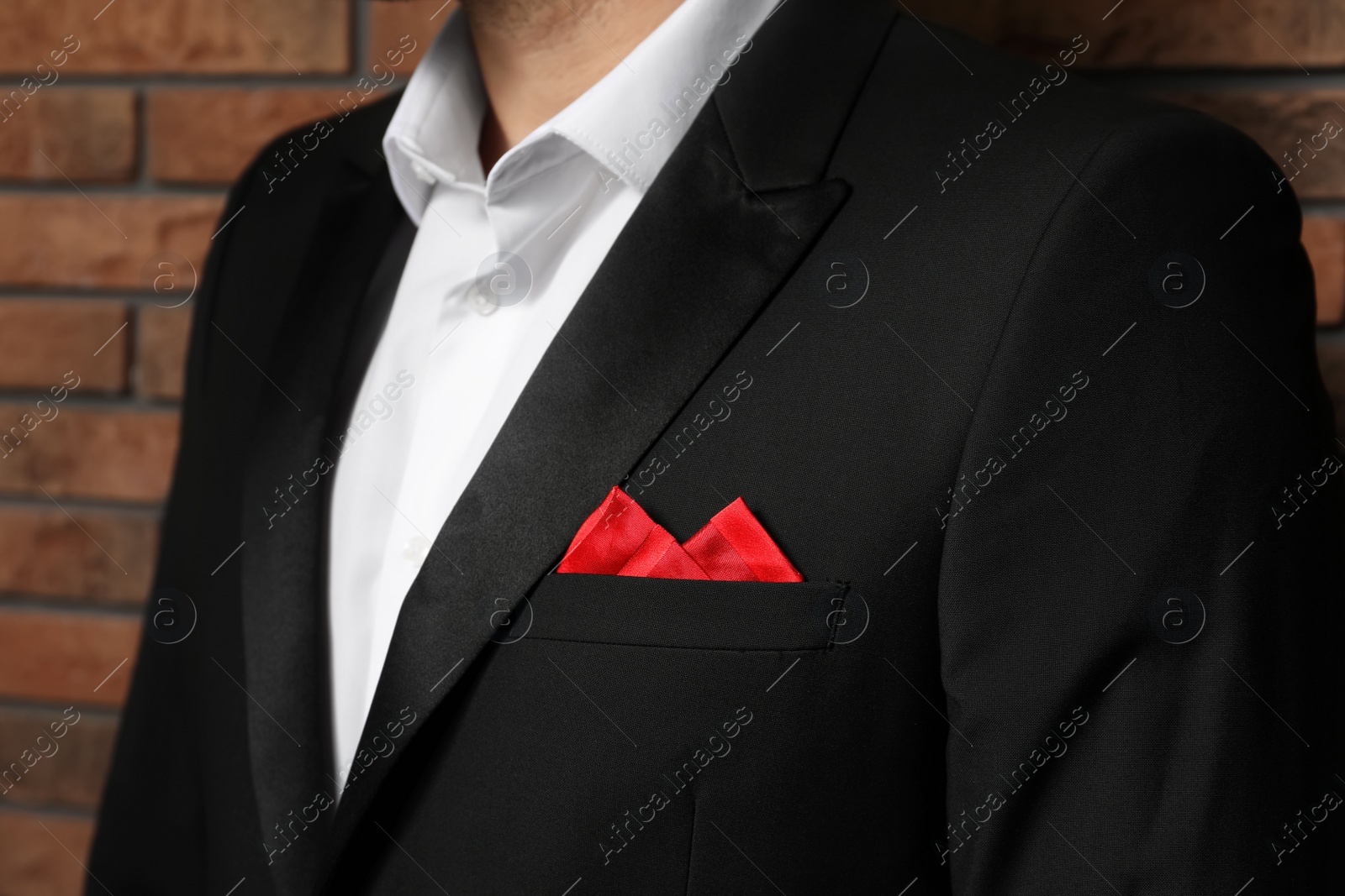 Photo of Man with handkerchief in breast pocket of his suit near brick wall, closeup