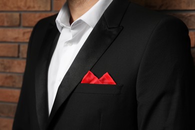 Man with handkerchief in breast pocket of his suit near brick wall, closeup